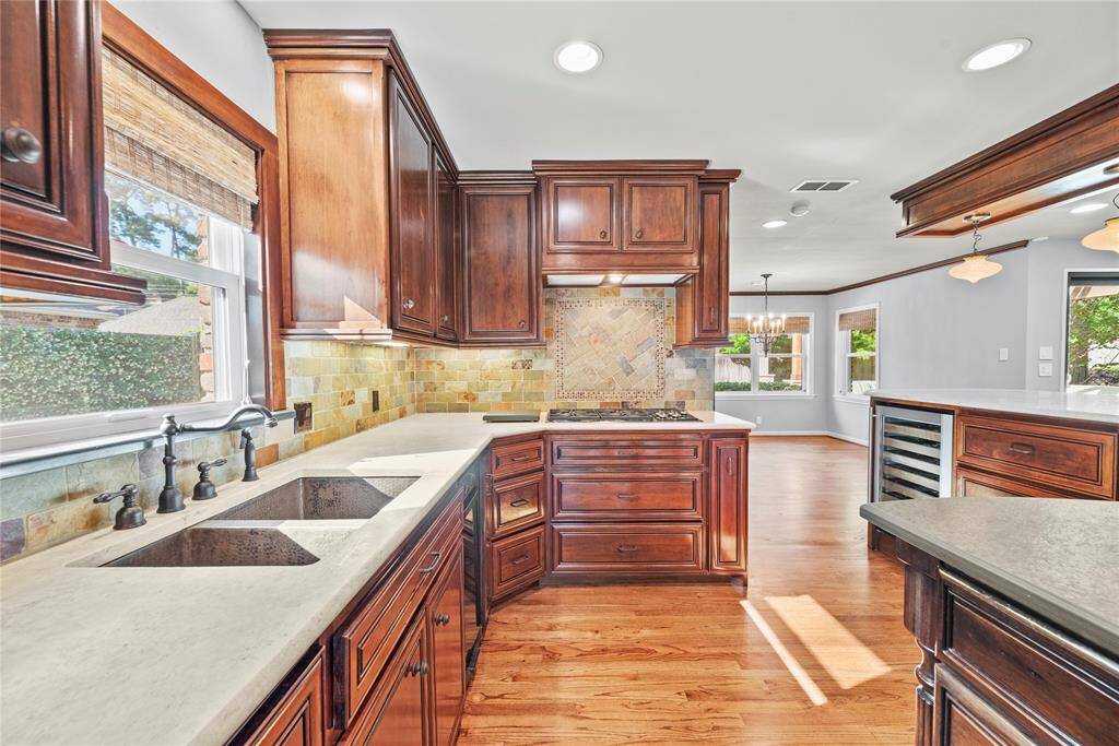 A beautifully updated kitchen featuring beautiful travertine counters, rich cabinetry, and high-end stainless steel appliances with room to entertain and gather.
