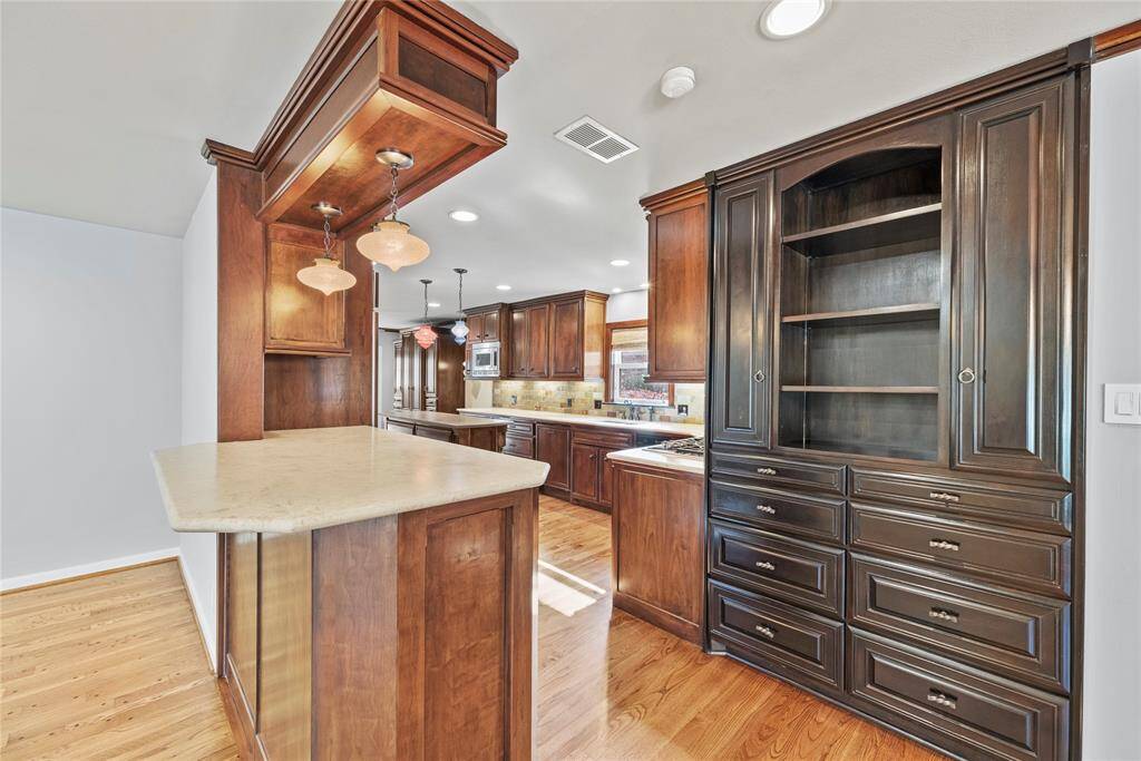 Custom wood cabinetry and a charming breakfast bar with pendant lighting create a warm, welcoming atmosphere for casual dining or morning coffee.