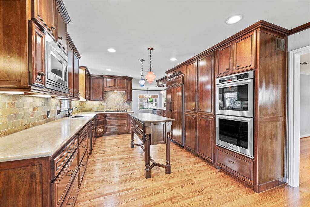 Custom wood cabinetry and a custom-made island with slate top adorned with elegant Murano glass pendant lighting create a warm, welcoming atmosphere.Double ovens are sure to please and Paneled Sub-Zero refrigerator continues the beauty.