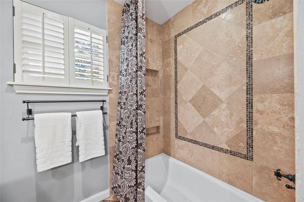 Close-up of the bath area featuring warm neutral tilework, built-in shower niches, and decorative tile framing for a polished finish.