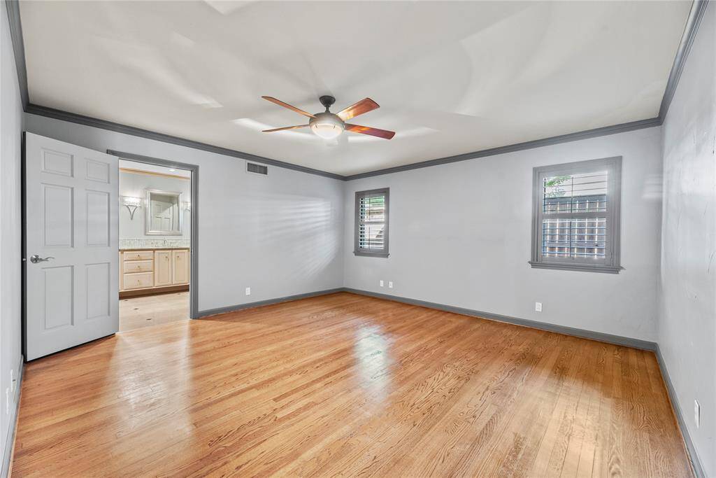 Spacious and serene, this primary retreat features rich hardwood floors, soft natural light, and elegant crown molding for a cozy yet elevated feel.
