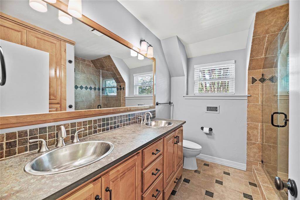 Secondary full bath on 2nd floor features double sinks resting in beautiful Slate countertops, attractive detailed tile work and large walk-in shower with seemless glass doors.