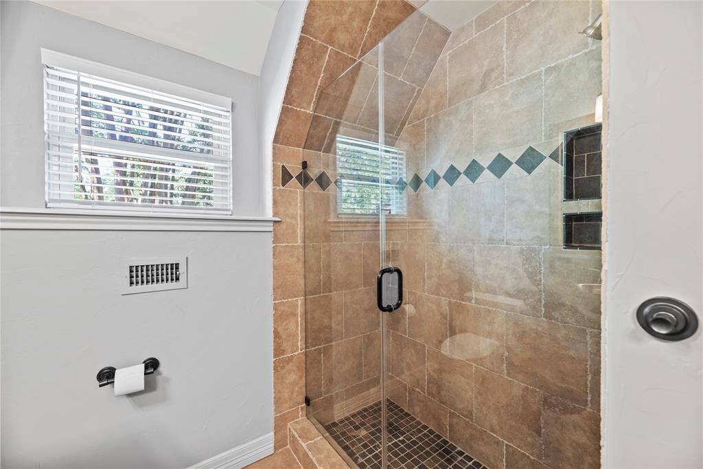 Custom walk-in shower with intricate tile detailing and glass enclosure, creating a spa-like experience at home.