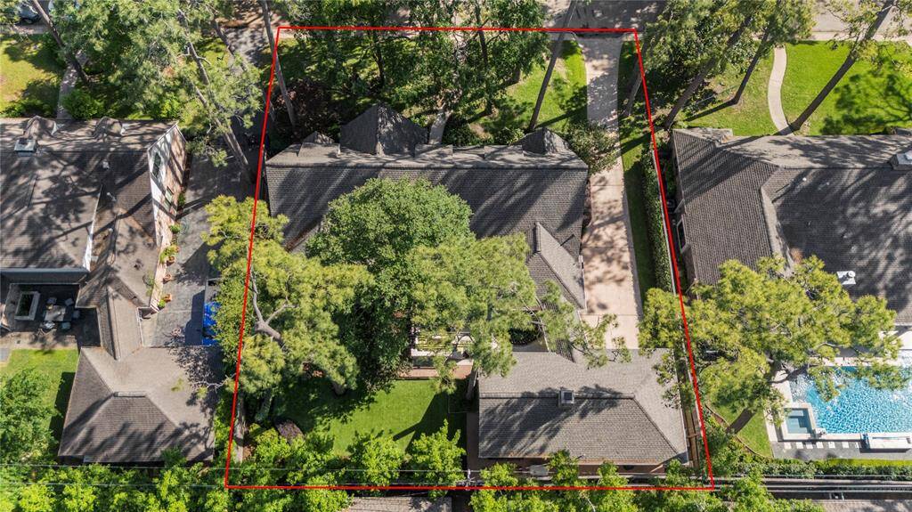 Bird’s-eye view showing the full property lot outlined in red—an expansive and private lot nestled among mature trees with generous front and backyards.