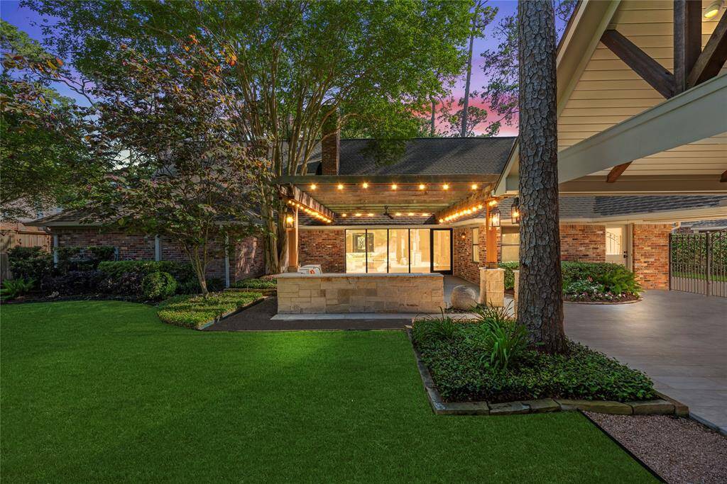 Twilight setting with string lights glowing from the pergola, creating an enchanting backyard ambiance under the canopy of trees.