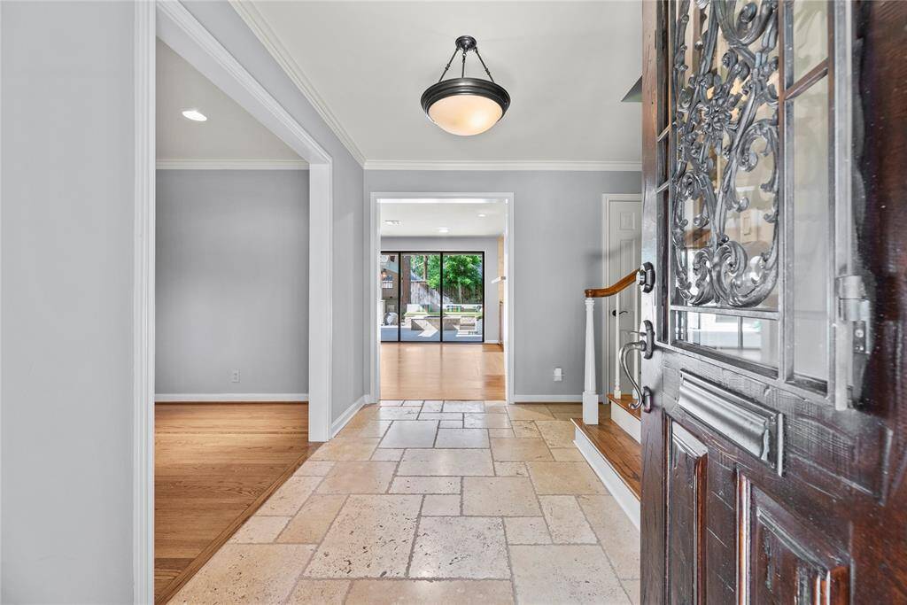Inviting entry with travertine floors leading into the main living area. A glimpse of the backyard oasis is visible through the window wall at the rear.