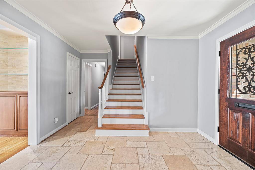 Straight-on view of the entry hall showcasing the wide staircase with wood treads and white balusters. Warm tones and fresh paint add to the home's charm.