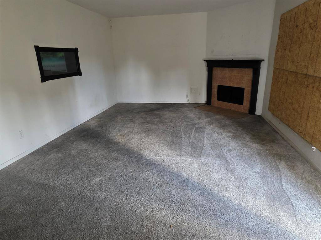 View of the living area with gas fireplace (broken window boarded up)