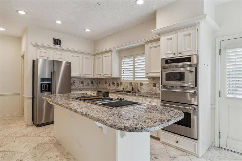 Spacious kitchen with island and breakfast bar. Open to the breakfast room and convenient access to the garage. Granite countertops, and stainless steel appliances.