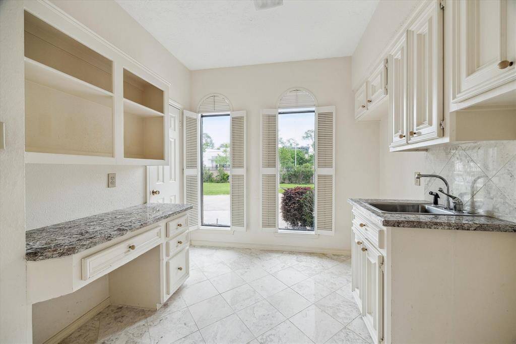 Spacious utility room with home office area, sink and plenty of storage.