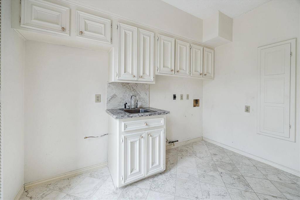 Another view of the laundry room with sink, storage, and refrigerator space.