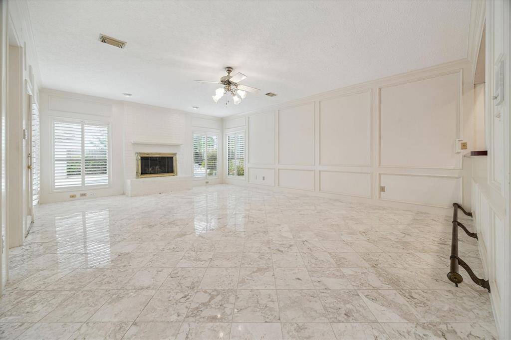 Spacious family room with a bar, view of the pool, fireplace, open to the formal dining room. Marble floors.