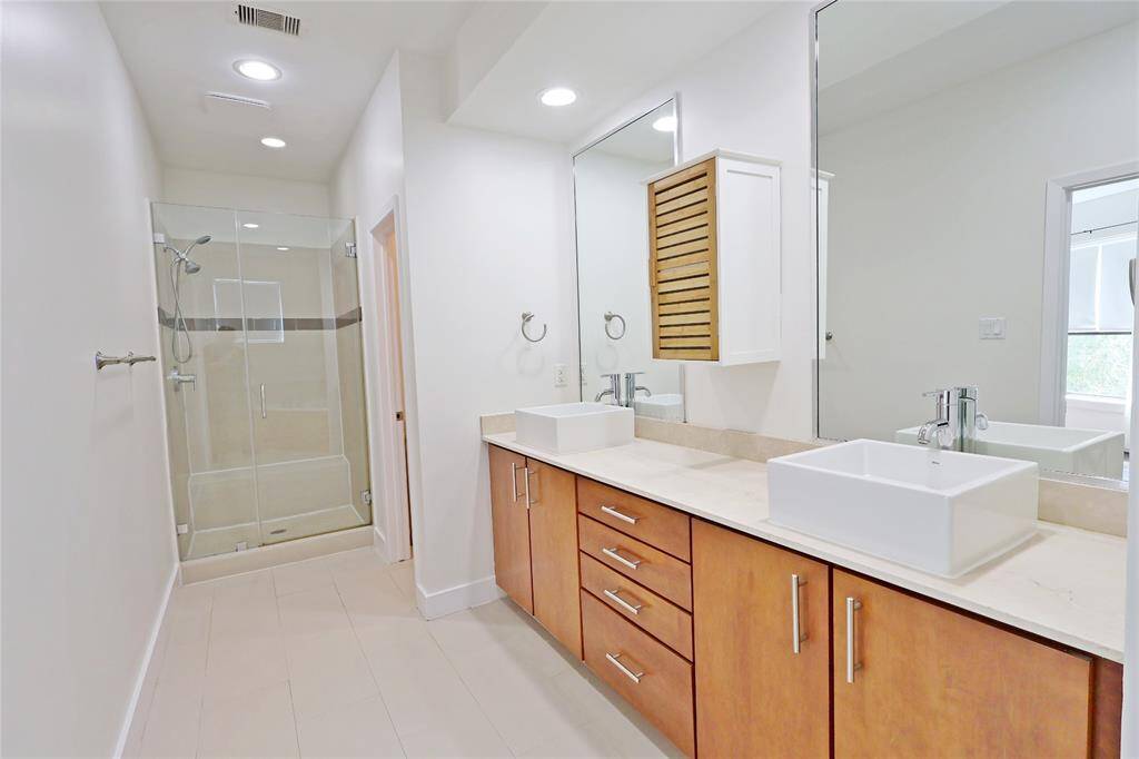 Above the sinks, large mirrors reflect the ambient light, enhancing the room's brightness and sense of space.