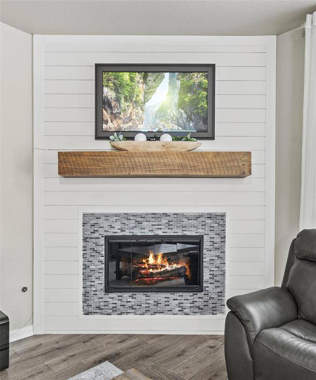 This cozy living area features a modern fireplace with ship lap, rustic wooden mantel. Sleek farmhouse style at its finest.