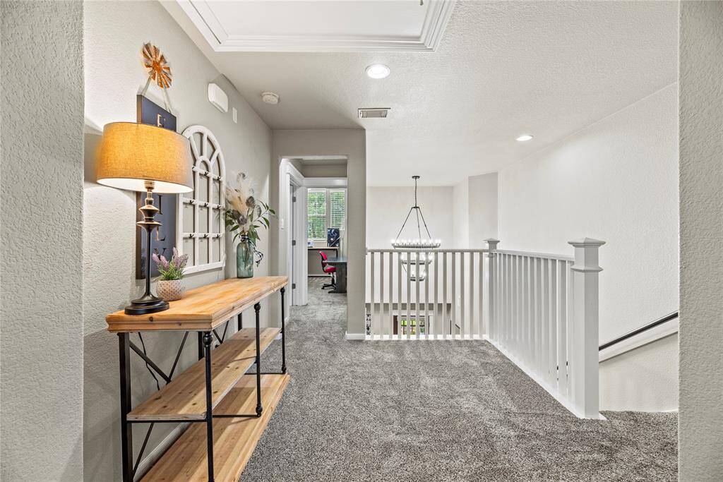 This photo shows a bright, well-lit landing area and features a white railing overlooking the staircase. Elegant and inviting.