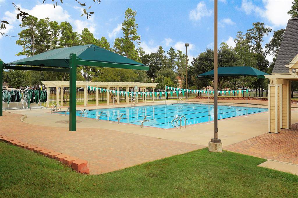 One of two Coles Crossing swimming pools with shaded seating areas, surrounded by lush greenery and a paved walkway, ideal for relaxation and recreation. There is another amazing set of amenities with a larger pool etc. It's a must see!