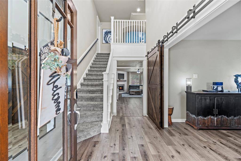 This welcoming entryway features a bright, open layout. An updated grand chandelier and a rustic sliding barn door adds character to the space as well.
