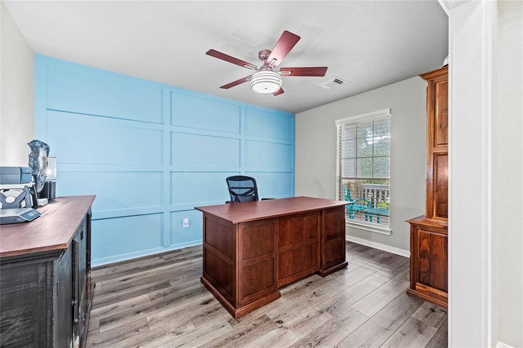 Bright home office with an accent wall, LPV flooring, and ample natural light with a nice view of the front of the home.