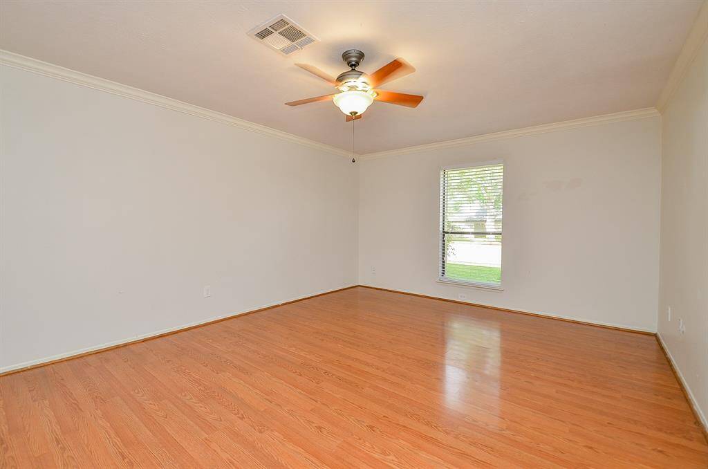 Spacious bedroom with large windows for natural light, elegant wood flooring, and a ceiling fan for comfort.