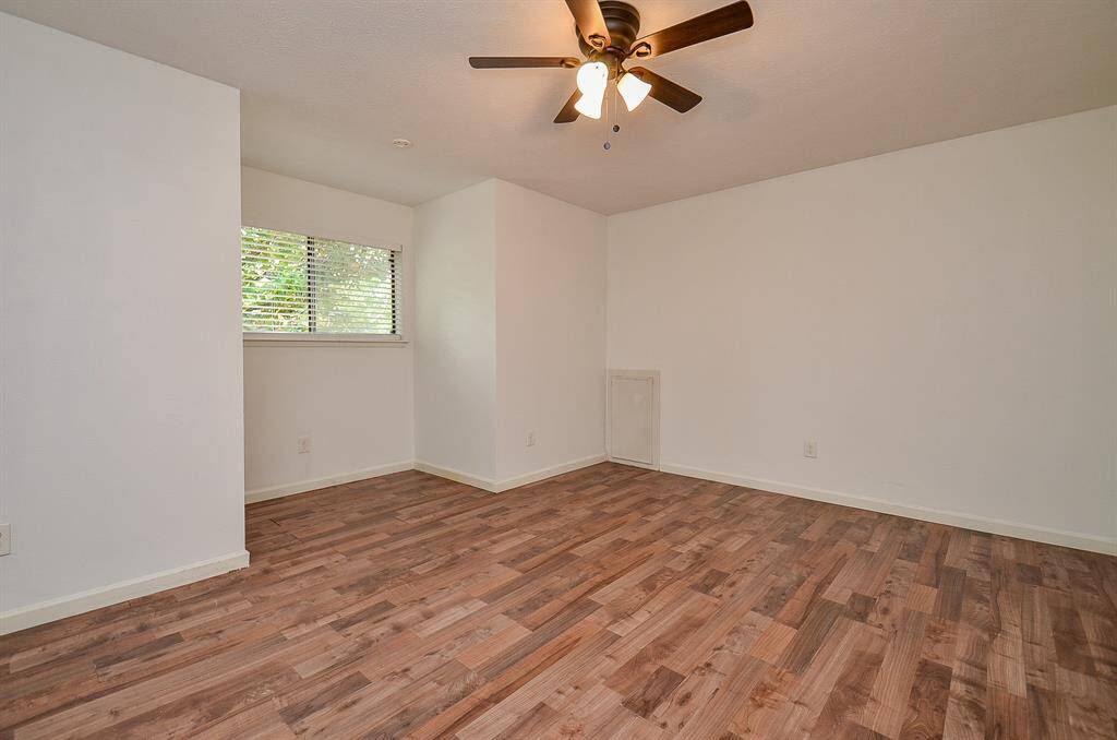 Spacious bedroom featuring elegant wood floors and a modern ceiling fan for comfort.