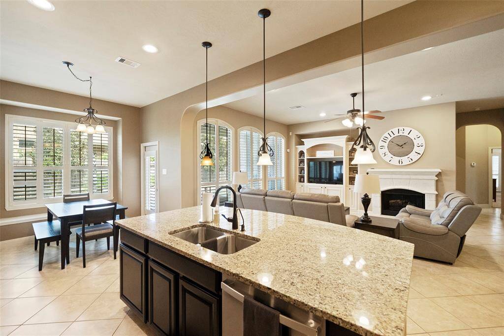 Open-concept kitchen flows effortlessly into the living area, ideal for entertaining with pendant lighting, breakfast nook, and expansive windows providing backyard views.