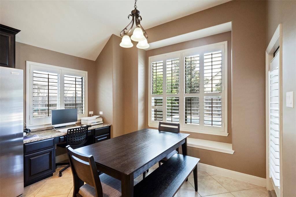 This functional space seamlessly combines a cozy dining area and a built-in granite-topped workspace. Whether you're enjoying a meal or working from home, the natural light and backyard views create a comfortable environment.