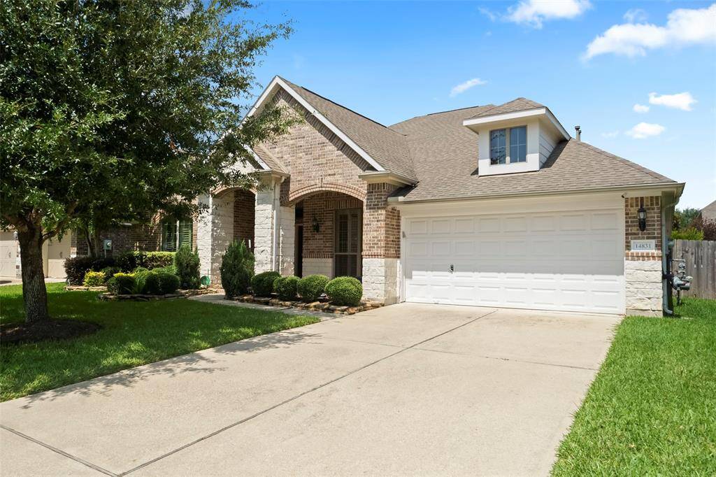 Charming brick and stone elevation with professional landscaping, mature tree, and spacious double driveway leading to a two-car garage—inviting curb appeal in a well-maintained neighborhood.
