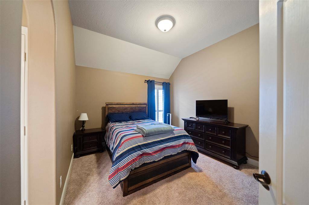 Guest bedroom featuring vaulted ceilings, soft-tone walls, and cozy ambiance. Ideal for visitors or as a secondary primary suite.