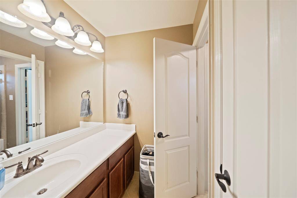 Bathroom with long vanity, dual sinks, framed mirror, and warm neutral tones—perfect for guests or family use with ample counter space and storage.