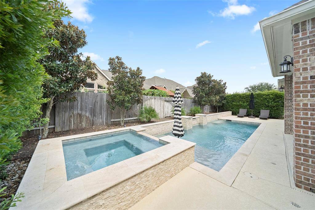 Relax and unwind in the luxurious raised spa with waterfall spillover into the resort-style pool. Surrounded by lush landscaping and privacy fencing for your own backyard oasis.