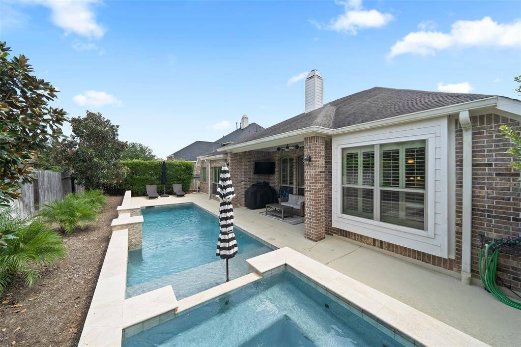 Inviting poolside view with a tranquil water feature, tanning ledge, and cozy lounge area—perfect for soaking up the sun or enjoying a quiet evening swim.