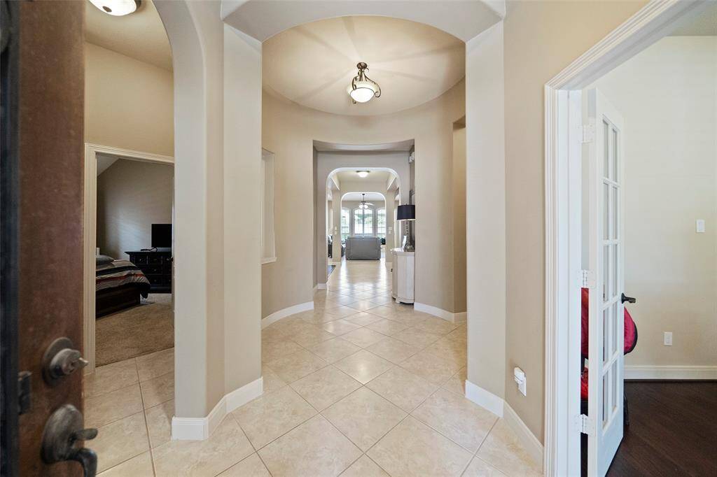 Elegant entry hall with soaring ceilings, tile floors, and arched architectural details leading into the heart of the home. A grand and graceful first impression.