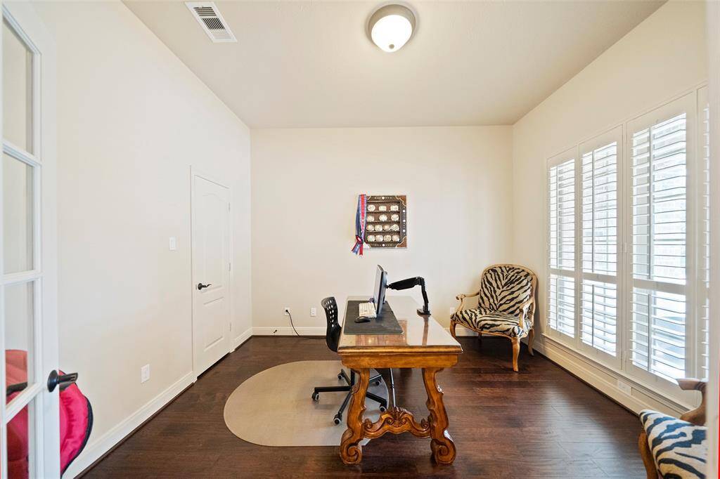 Dedicated home office with rich wood floors, large windows with plantation shutters, and French doors—ideal for working from home in a bright and private space.