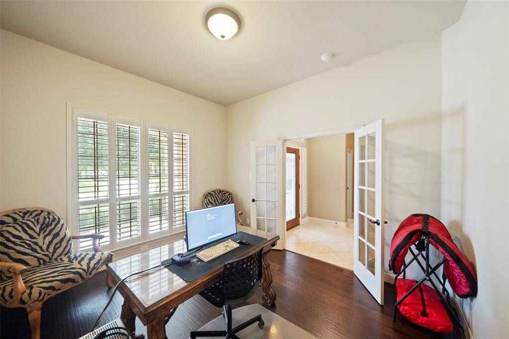 Alternate angle of the office space highlighting the open flow to the entry hall and abundant natural light from the front-facing windows.