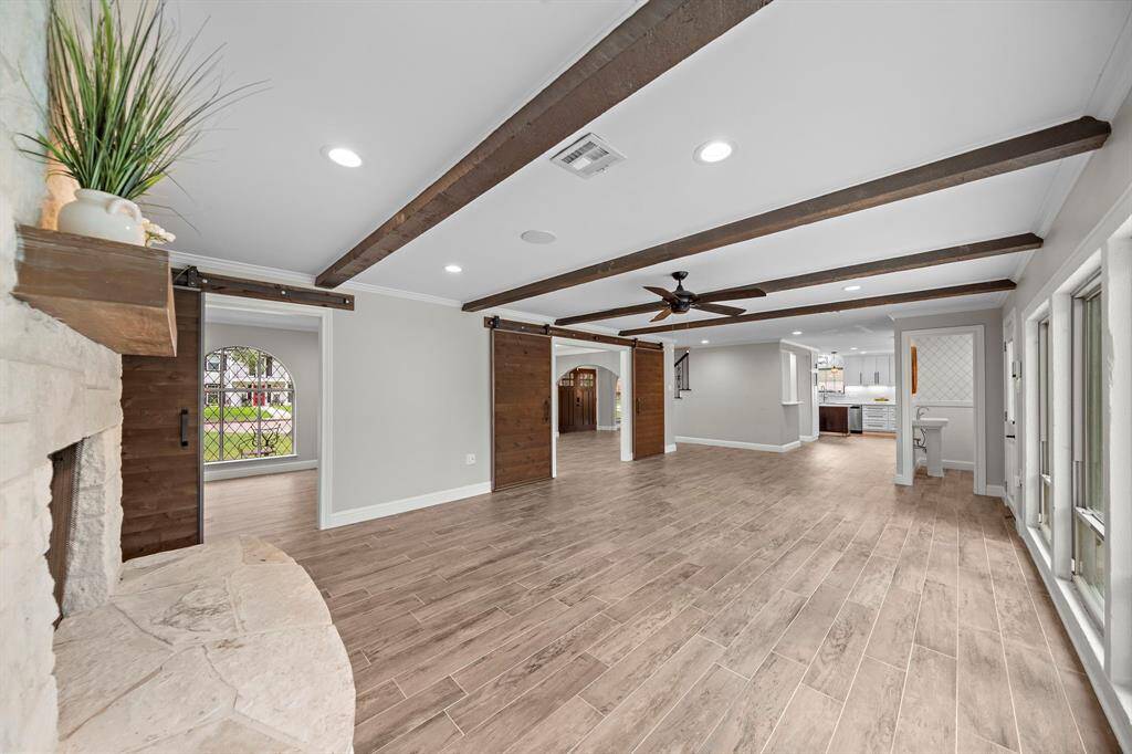 Experience elegance with porcelain wood-look tile floors and ambient recessed lighting throughout the main level, featuring a conveniently located powder room to the right.