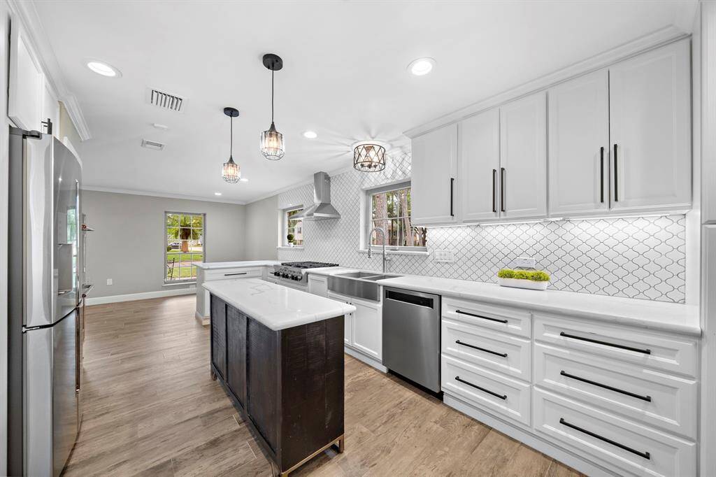 Discover culinary bliss in this stunning kitchen, featuring a decorative backsplash, stainless farmhouse sink, and a custom island with quartz countertops. Enhanced by recessed, pendant, and undercounter lighting.