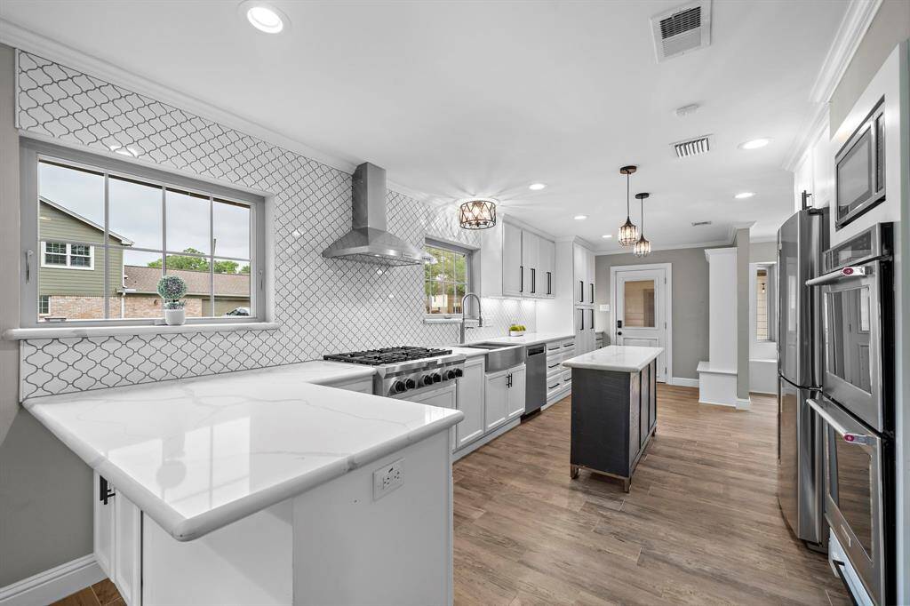 Experience luxury in this beautifully remodeled kitchen, featuring quartz countertops with a bar, a KitchenAid gas cooktop with vent hood, double electric ovens, and a dishwasher. Includes a Samsung stainless steel refrigerator.