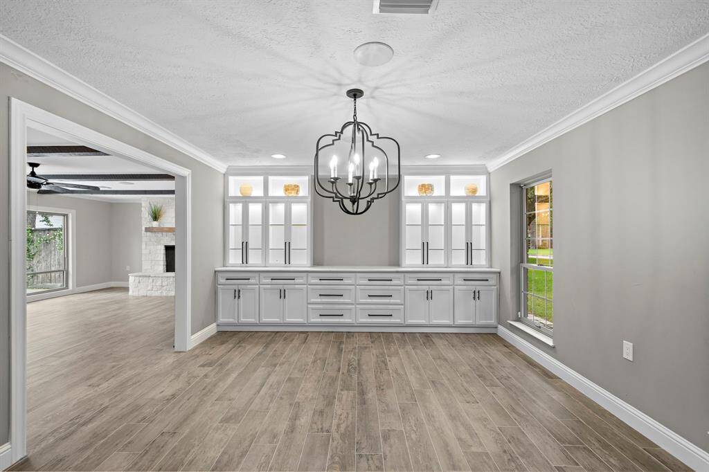 This dining room features elegant custom cabinetry with a quartz countertop for serving and illuminated upper cabinets for a stunning ambiance.