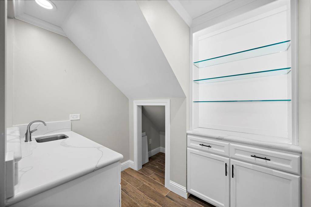 Discover the elegant wet bar featuring illuminated cabinetry and sleek quartz countertops. Under the stairs is the perfect spot for wine storage (electrical for a small wine refrigerator).
