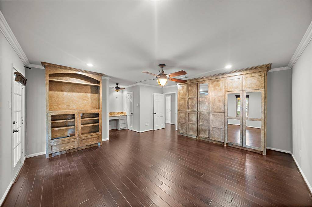 The primary suite has custom built in cabinets and a vanity area with granite countertop.  The door next to vanity leads to the walk in closet.