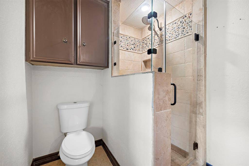 The primary suite bathroom with tiled shower and frameless glass door.