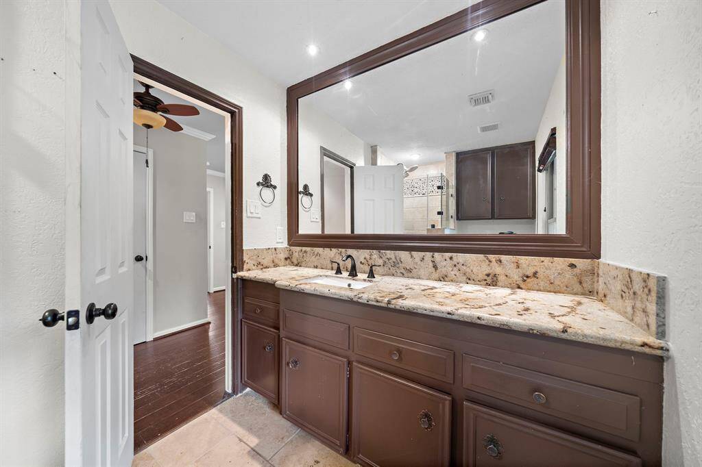 The primary bathroom with granite countertop and travertine floor.