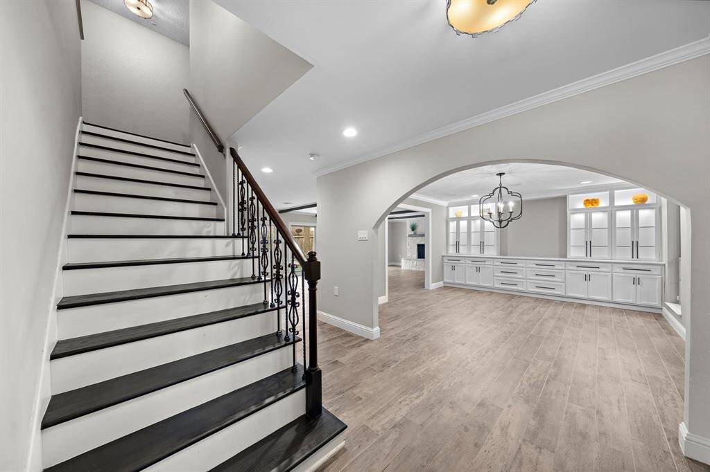 Discover the elegance of the dining room through a charming archway, featuring custom lighted cabinetry.