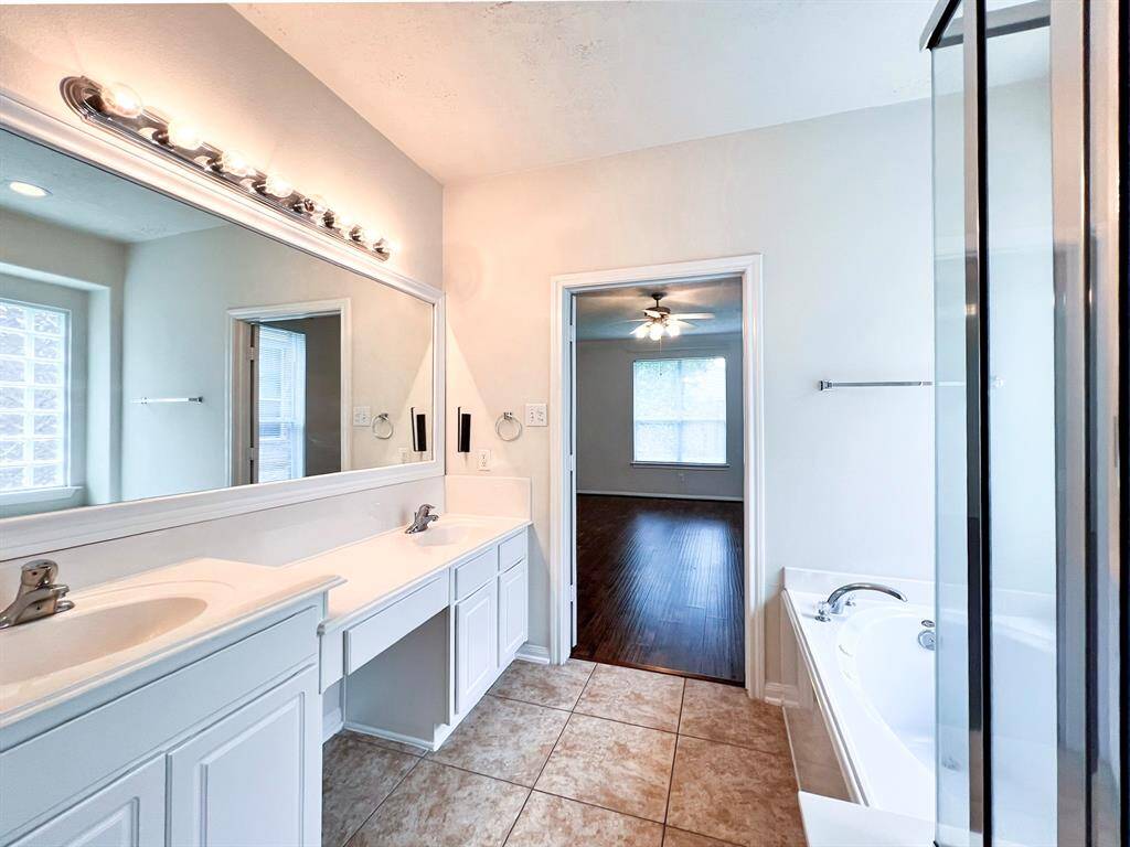 Primary bathroom featuring dual vanities and access to a spacious closet.