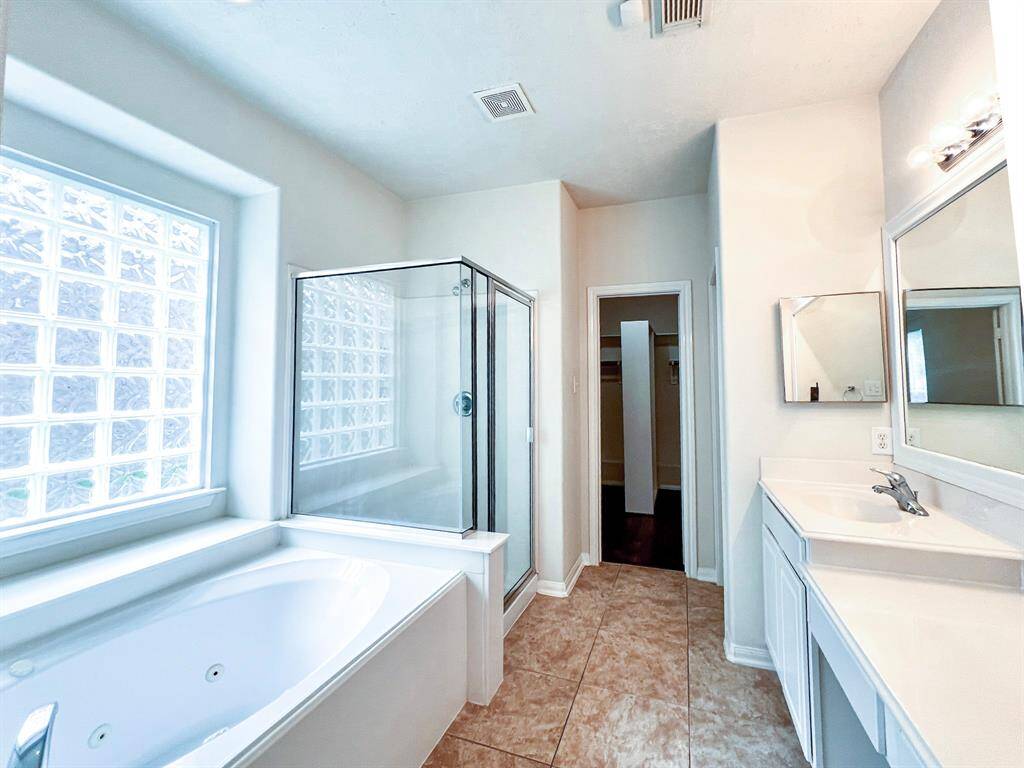 Another view of the primary bathroom showing the separate tub and walk-in shower.