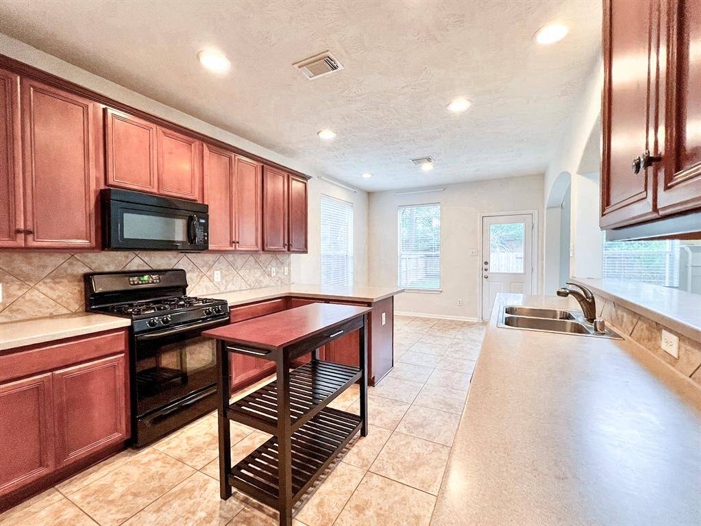 Bright kitchen with a view towards the breakfast nook, featuring ample counter space and cabinetry.
