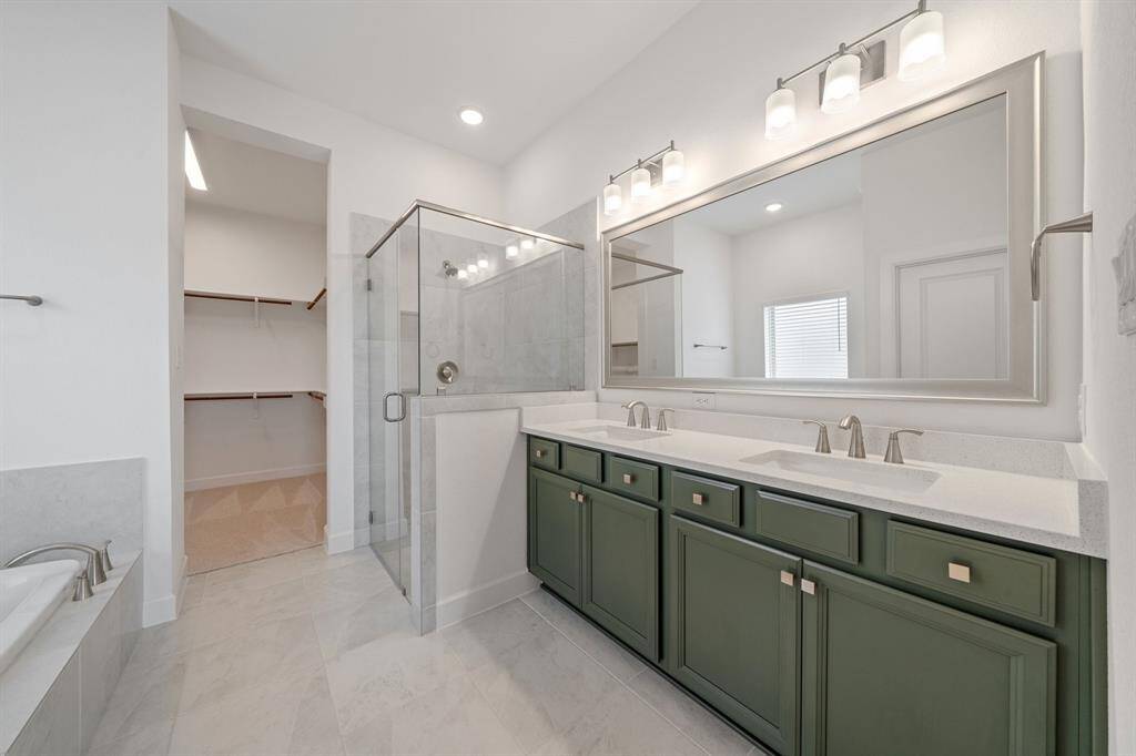 A simple yet sophisticated design, with sleek double-sink vanities that exude modern elegance. Dark green cabinets add a refined touch that enhances the cozy and inviting ambiance of it all.