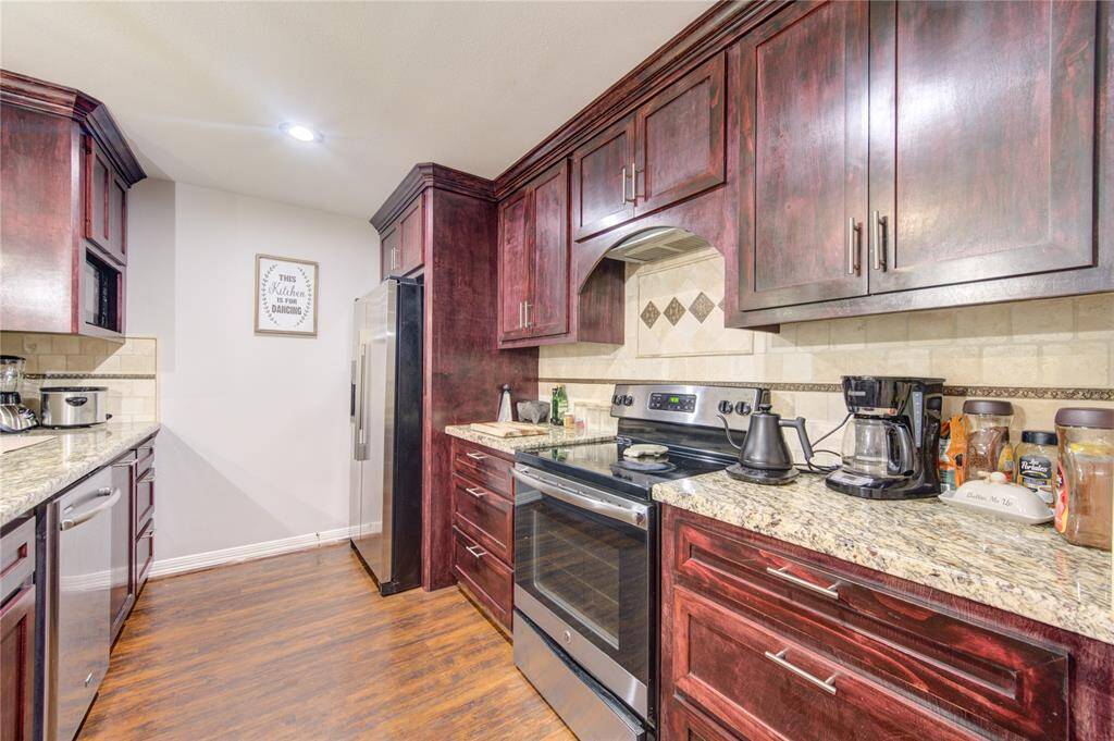 tainless steel appliances and a stylish tiled backsplash add a modern touch, while hardwood floors and contemporary pendant lighting complete the space with both functionality and flair.