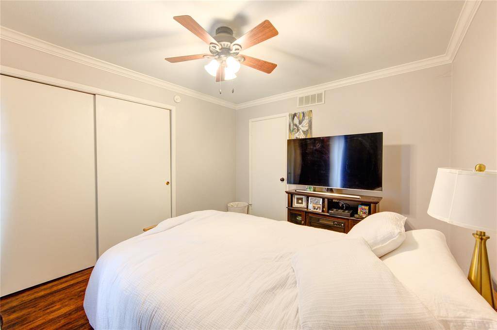 Relax in this cozy bedroom, showcasing polished hardwood floors and a ceiling fan for comfort. The spacious closet and large window provide both practicality and natural light, while the clean, neutral color scheme offers a perfect backdrop for personalization.