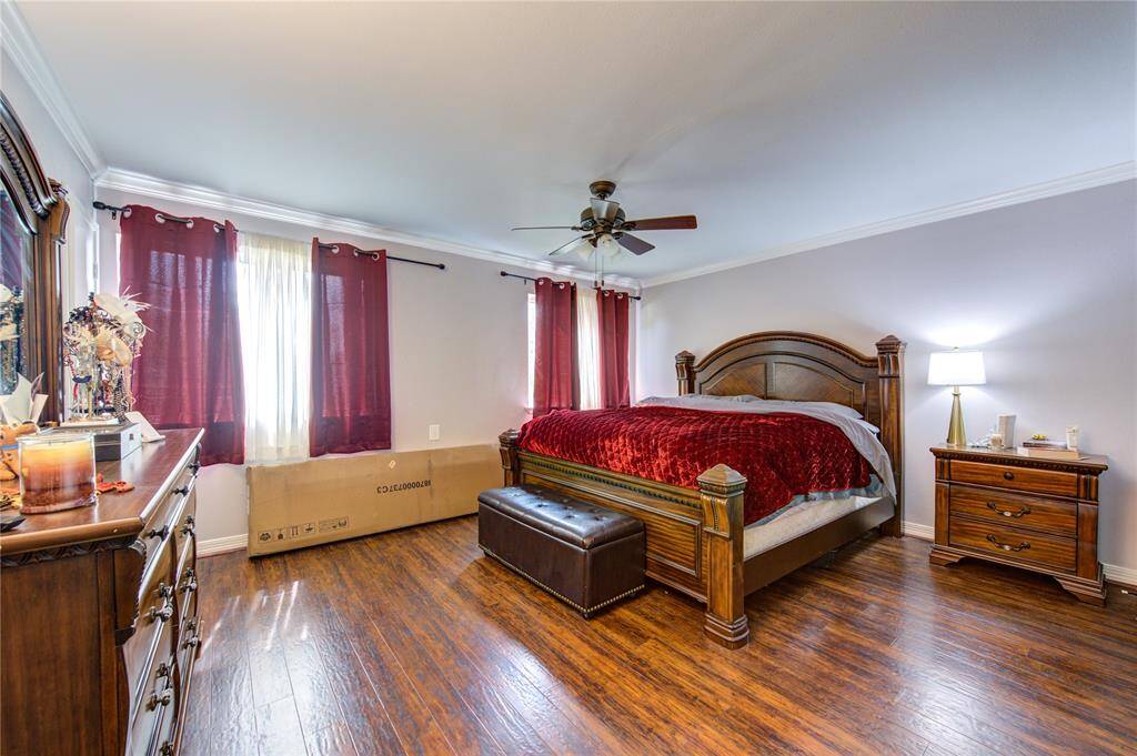 Welcome to this cozy bedroom featuring laminate floors and a soothing neutral color palette. A ceiling fan enhances comfort, while ample natural light streams in through a window dressed with elegant dark curtains, creating a serene and inviting atmosphere.